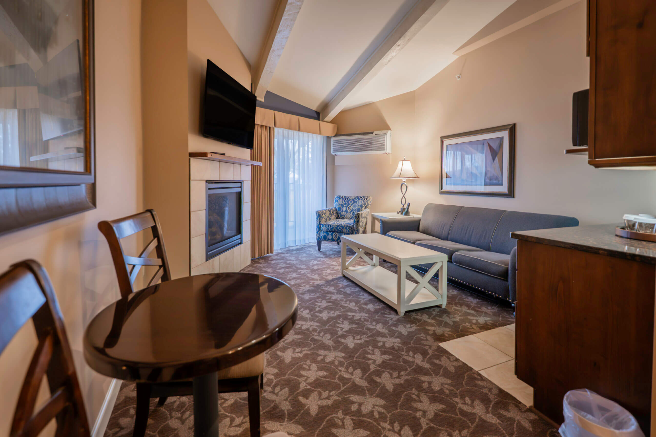 Lakewood Coastal Suite living area with a sofa, fireplace, and dining space, Lake Lawn Resort