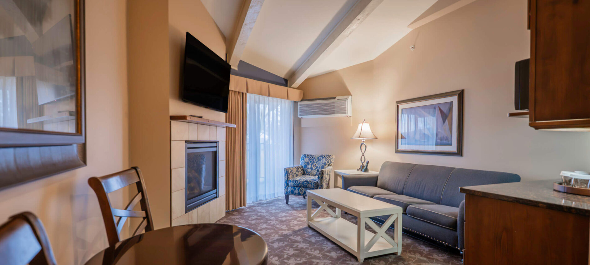 Lakewood Coastal Suite living area with a sofa, fireplace, and dining space, Lake Lawn Resort