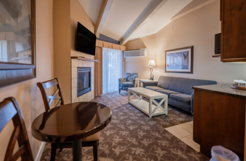 Lakewood Coastal Suite living area with a sofa, fireplace, and dining space, Lake Lawn Resort