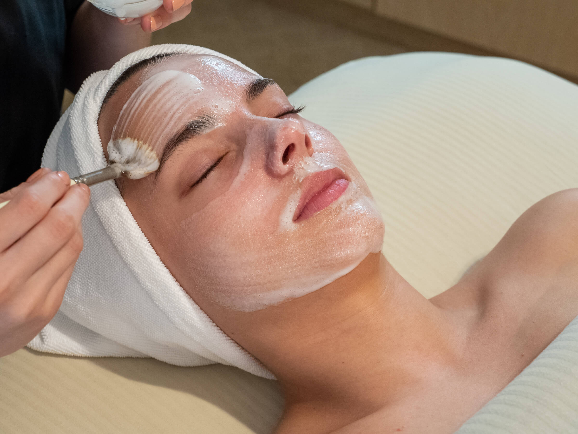 Beautiful brown haired woman getting a facial at Calladora Spa. The aesthetician is putting a mask on the guest.