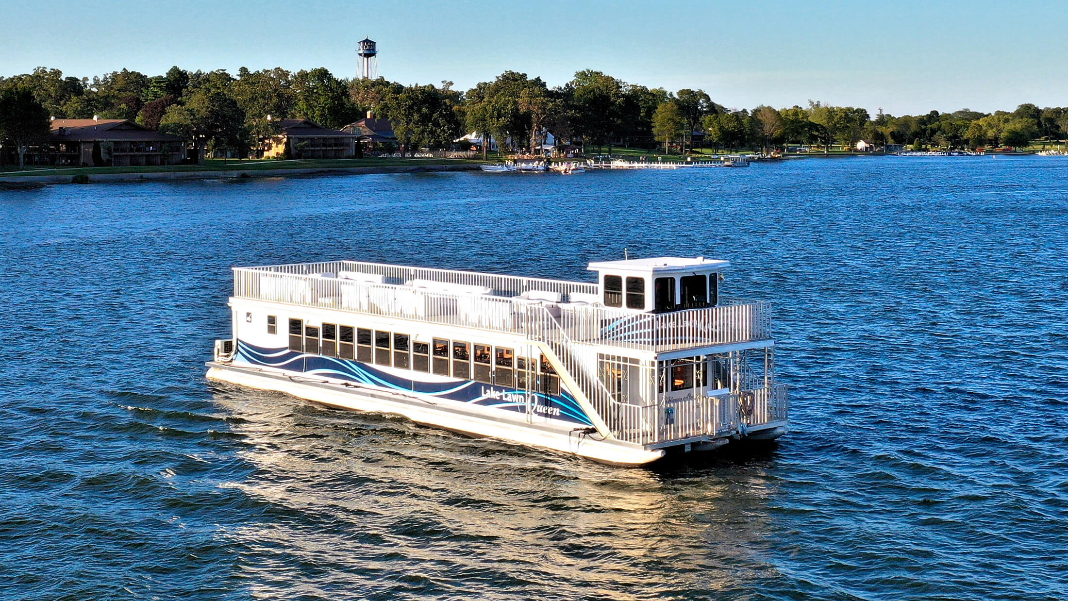 The Lake Lawn Queen tour boat cruising on Delavan Lake past the Lake Lawn Resort shoreline and water tower
