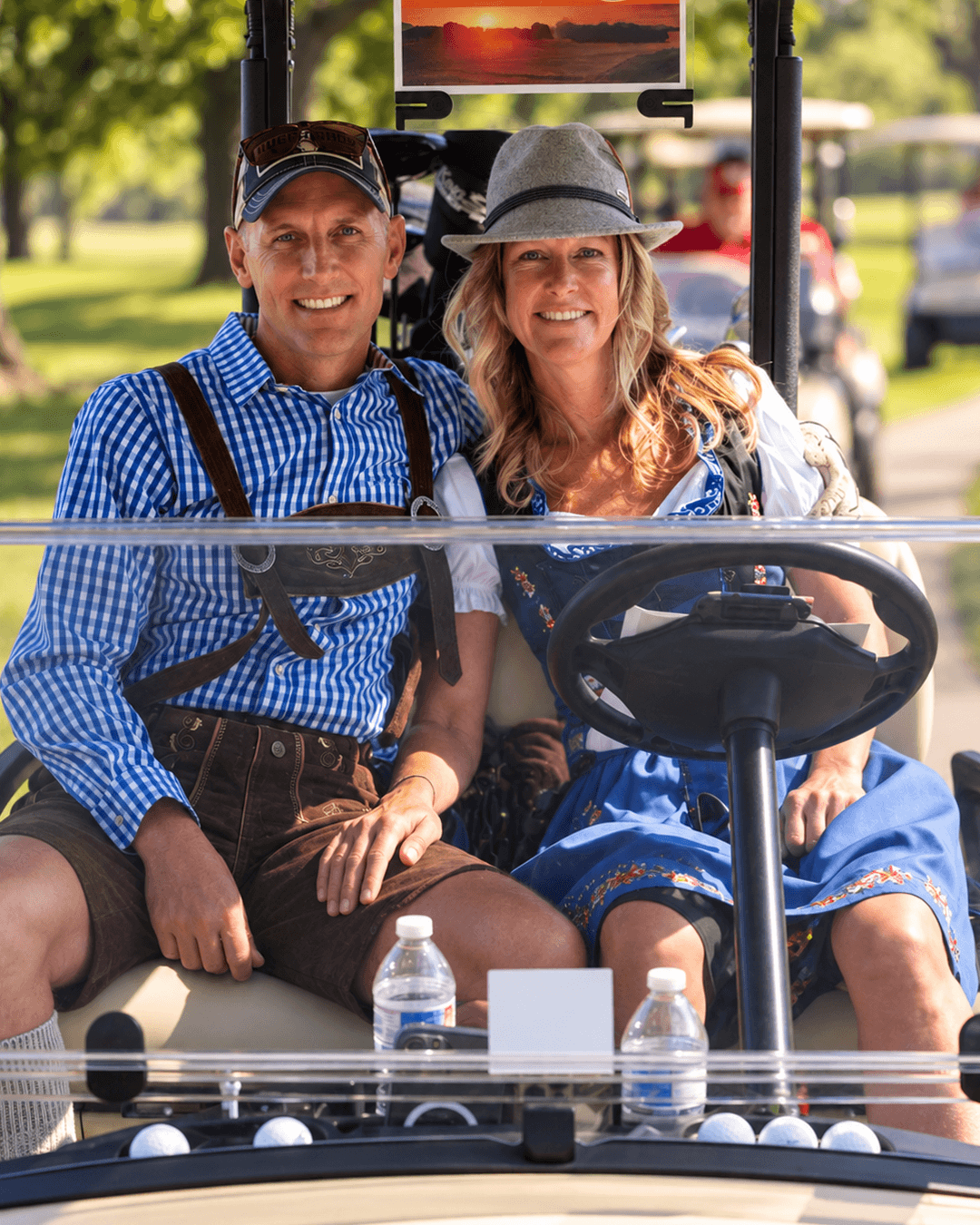 Two golfers in Oktoberfest attire in a golf cart at the Craft Brew Open